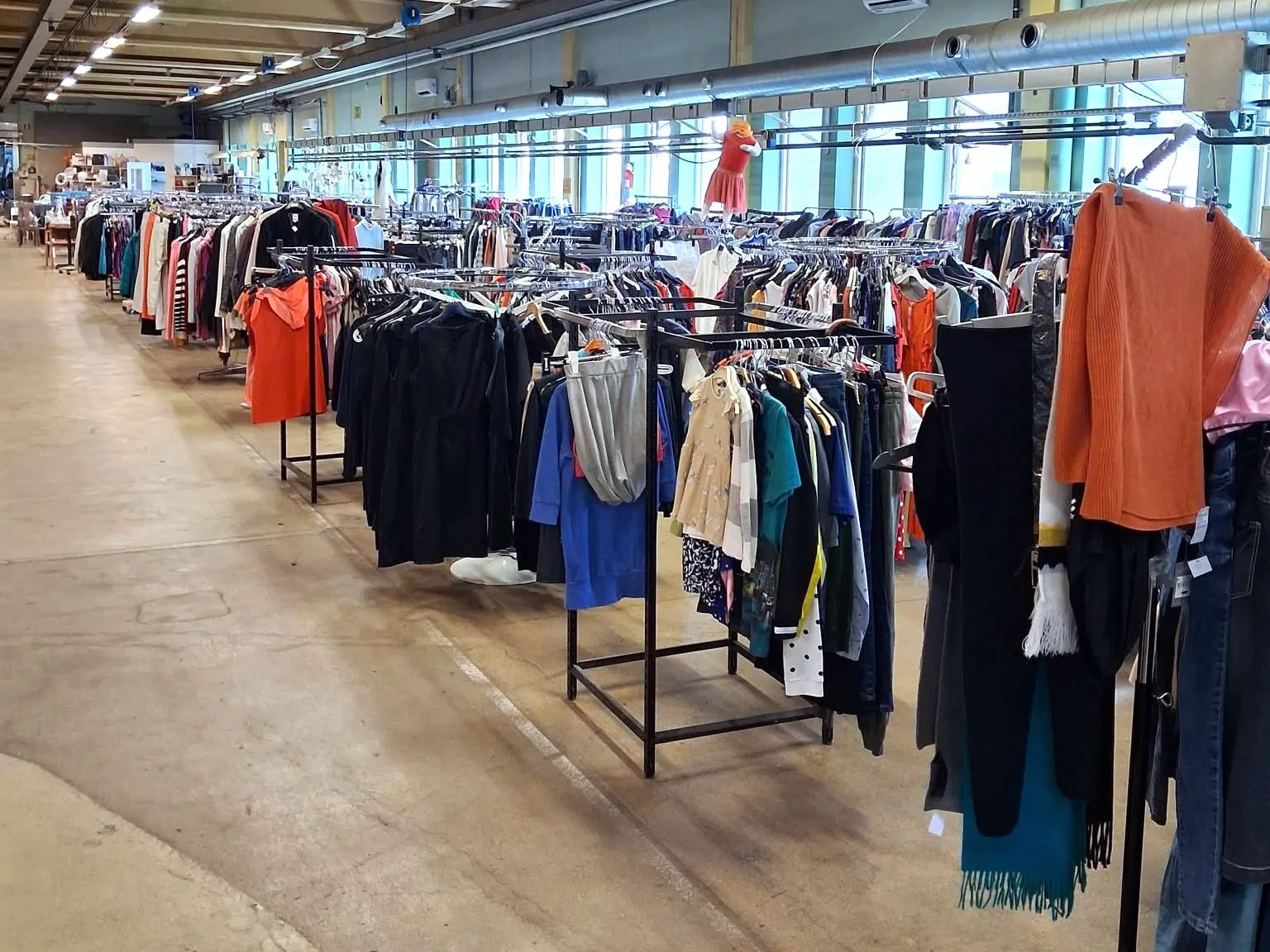 Långa rader med klädställningar under lysrör i Emmpatus Åkvarns second hand-butik i Torpsbruk