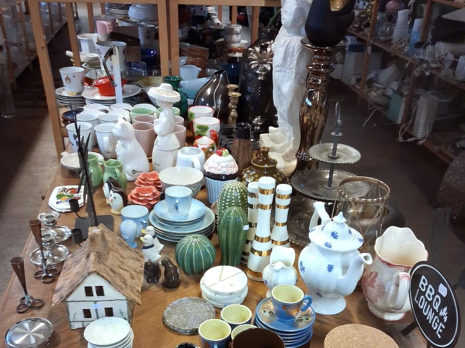 Bord fullt av porslin, keramik och ljusstakar i Emmpatus Åkvarns second hand-butik i Torpsbruk