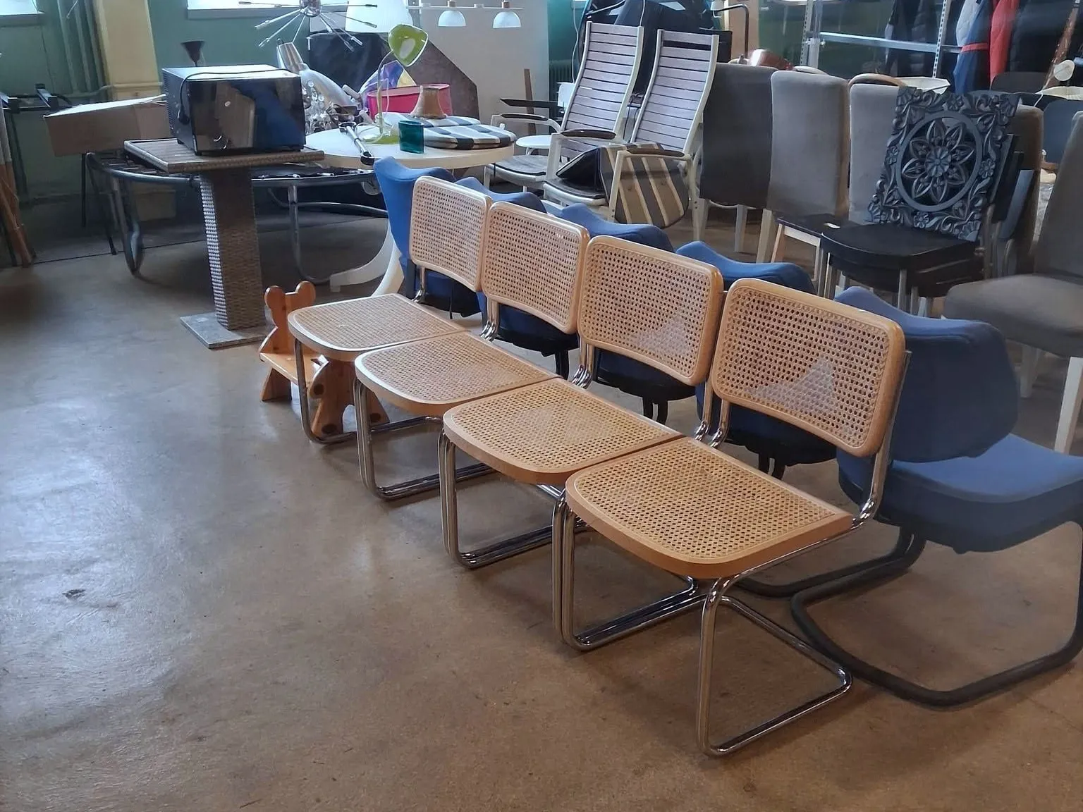 Fyra rottingstolar på rad på betonggolvet i Emmpatus Åkvarns second hand-butik i Torpsbruk